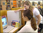 Photo of librarian helping a patron use an information station